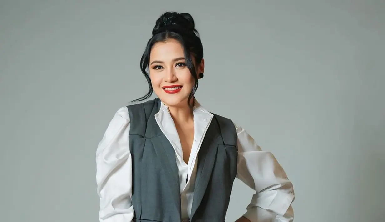 Tampil dengan kemeja putih dipadukan dengan blazer abu-abu dan kain lilit sebagai bawahannya, Fera Feriska bikin pangling. Rambut pemeran Dinda Lestari di sinetron Love Story The Series ini dicepol dengan juntaian di kiri dan kanannya. Makeup-nya flawless, namun Fera memoles bibirnya dengan lipstik warna merah yang membuat pesonanya semakin terpancar. (Liputan6.com/IG/@_feraferiska_)