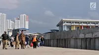 Wisatawan berjalan di dekat tanggul laut di Pelabuhan Kali Adem, Muara Angke, Jakarta, Selasa (12/2). Pembangunan tanggul laut tersebut merupakan bagian dari program Pengembangan Terpadu Pesisir Ibukota Negara atau NCICD. (Merdeka.com/Iqbal S. Nugroho)