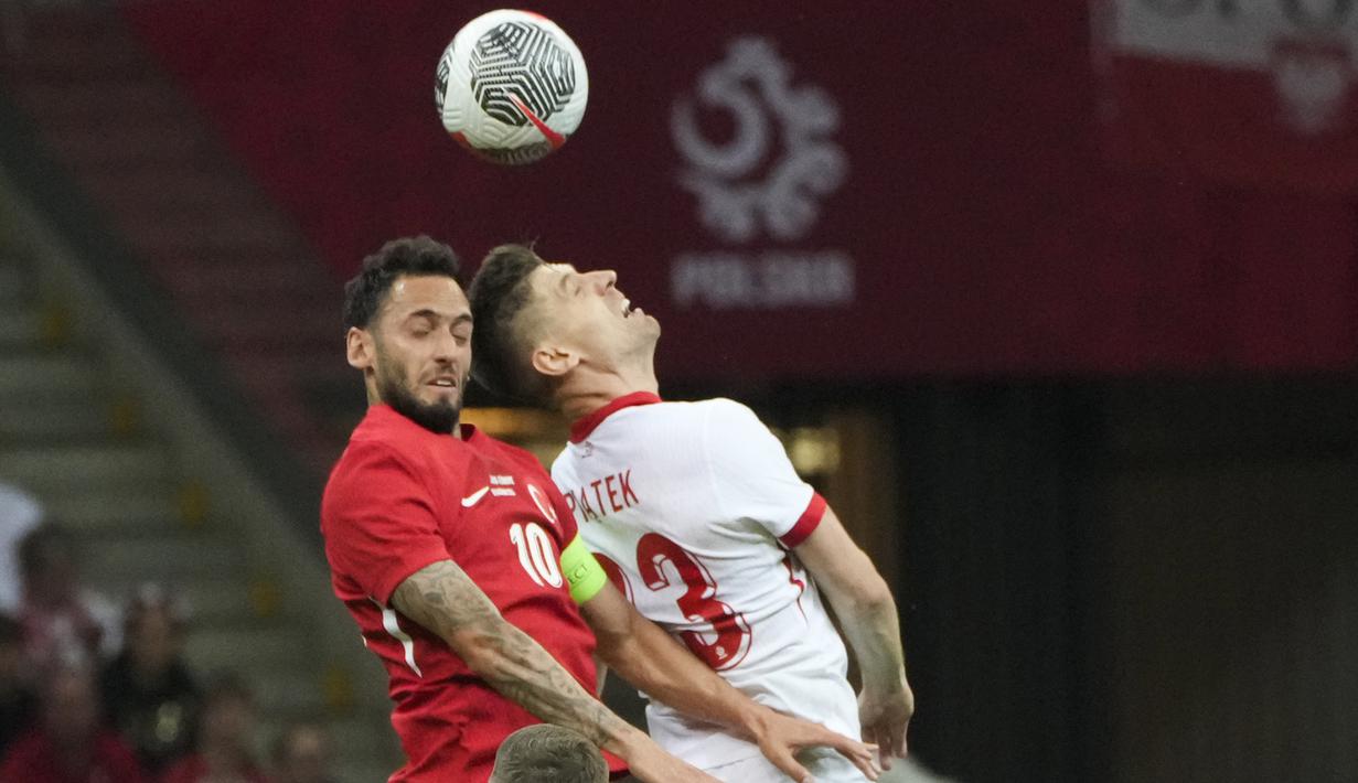 Penyerang Polandia Krzysztof Piatek berebut bola dengan gelandang Turki Hakan Calhanoglu dalam laga uji coba internasional terakhir jelang Euro 2024 di National stadium, Warsaw, Selasa (11/6/2024). (AP Photo/Czarek Sokolowski)