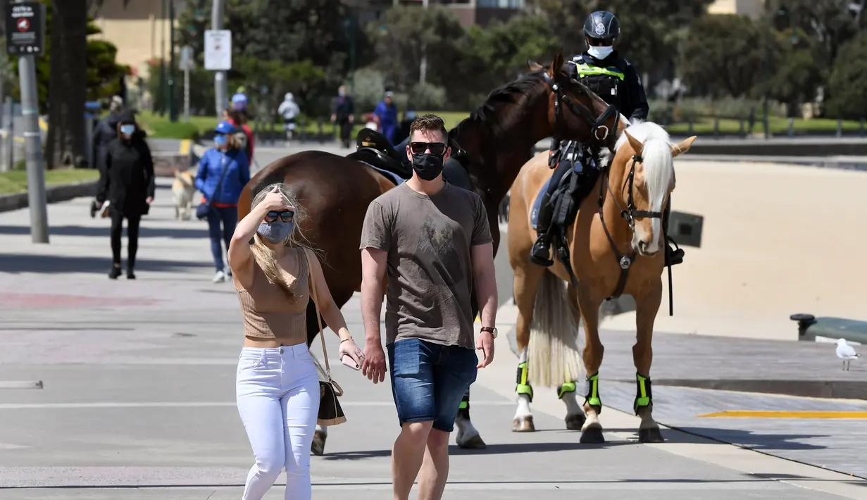 Polisi berpatroli dengan menunggang kuda di sepanjang St Kilda Esplanade di Melbourne (26/10/2020). Australia telah menghabiskan berbulan-bulan di bawah pembatasan yang berat setelah menjadi episentrum gelombang kedua negara itu. (AFP Photo/William West)