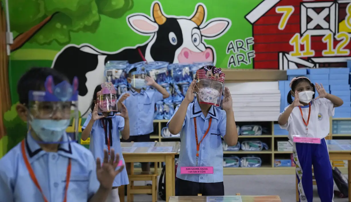 Siswa dengan masker dan pelindung wajah mengikuti hari pertama kelas tatap muka di sekolah dasar Comembo di kota Makati, Filipina, Senin (6/12/2021). Beberapa sekolah di Manila diizinkan dibuka kembali setelah berbulan-bulan lamanya karena kasus COVID-19 terus menurun. (AP Photo/Aaron Favila)