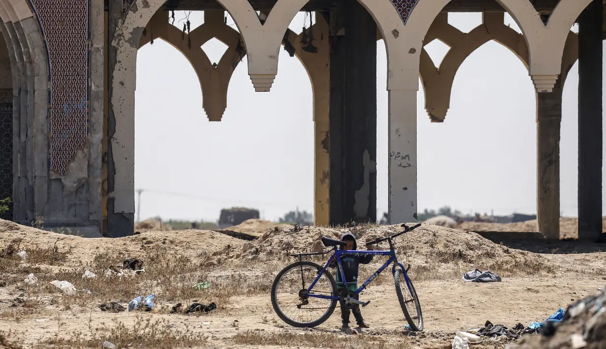 Seorang anak bermain di depan terminal "Yasser Arafat International Airport" yang hancur dan sepi di Jalur Gaza, di kota Rafah, Palestina (24/6/2019). Otoritas Palestina menyatakan sudah memboikot pertemuan di Bahrain yang akan dimulai pada Selasa (25/6) pekan depan. (AFP Photo/Said Khatib)