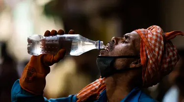 Pekerja meminum air dari botol di tengah meningkatnya suhu di New Delhi, India, Rabu (27/5/2020). India dilanda gelombang panas dan krisis air bersih di tengah upaya menangani pandemi virus corona COVID-19. (Jewel SAMAD/AFP)