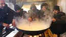 Para imigran memasak dalam tempat penampungan sementara di Kamp Lipa, luar Bihac, Bosnia, Jumat (8/1/2021). Cuaca bersalju dan musim dingin telah membawa lebih banyak penderitaan bagi ratusan imigran yang terjebak selama berhari-hari di kamp tersebut. (AP Photo/Kemal Softic)