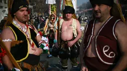 Sejumlah pria mengenakan kostum saat mengikuti Festival Internasional Masquerade Games di Pernik, Bulgaria (28/1). Para peserta selain mengenakan topeng dan kostum mereka juga membawa lonceng. (AFP/Nikolay Doychinov)