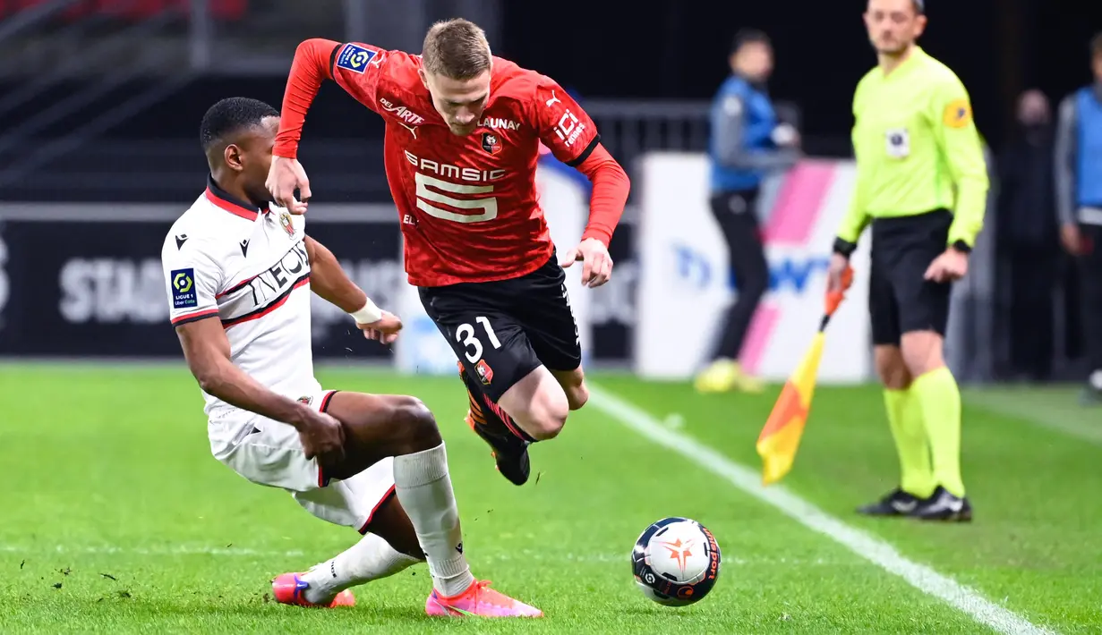 Bek Rennes, Adrien Truffert (kanan) berebut bola dengan striker Nice, Myziane Maolida dalam laga lanjutan Liga Prancis 2020/21 pekan ke-27 di Roazhon Park Stadium, Rennes, Jumat, (26/2/2021). Rennes kalah 1-2 dari Nice. (AFP/Damien Meyer)