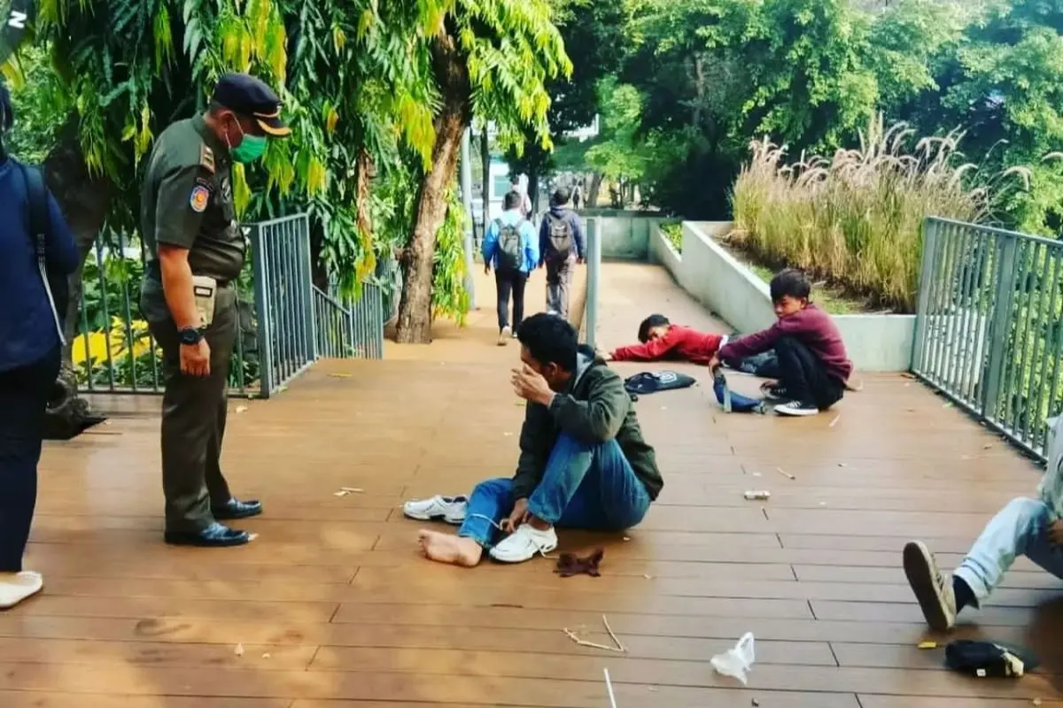 Satpol PP DKI Jakarta membangunkan para remaja yang tertidur