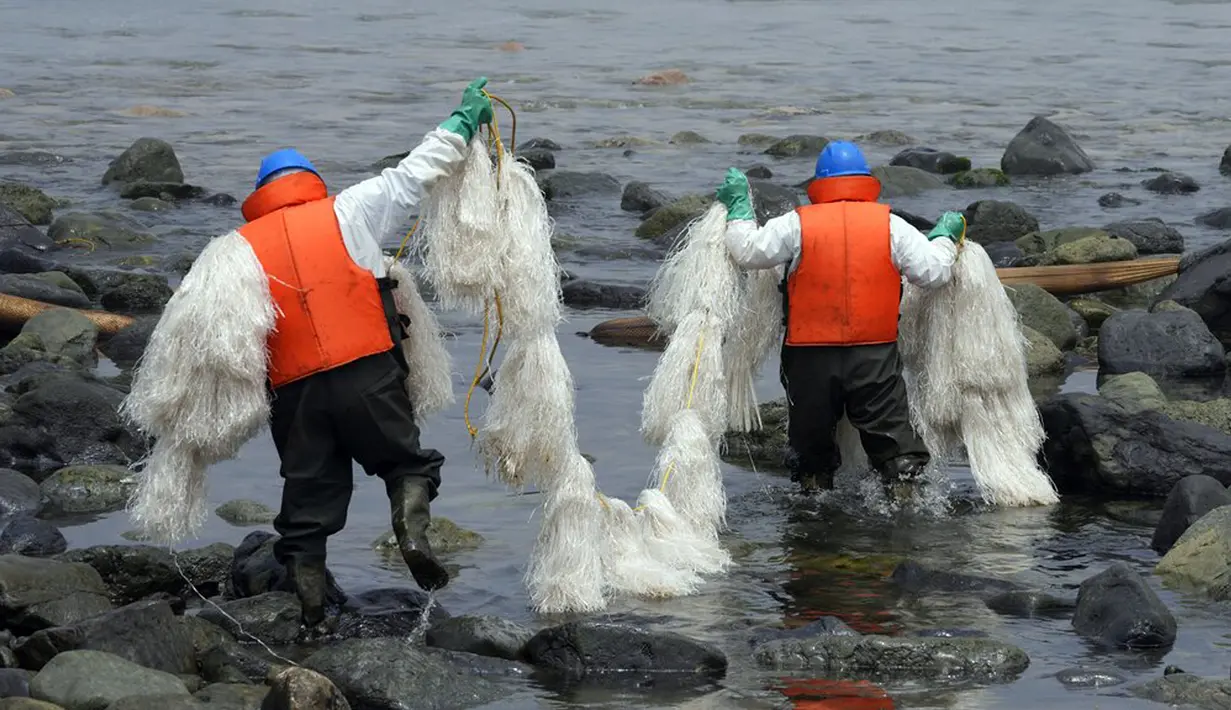 Pekerja membawa sejenis skimmer untuk mengumpulkan limbah minyak saat kampanye pembersihan di Pantai Pocitos, Ancon, Peru, 15 Februari 2022. Sebulan berlalu, pekerja melanjutkan pembersihan di pantai setelah terkontaminasi tumpahan minyak Repsol. (AP Photo/Martin Mejia)