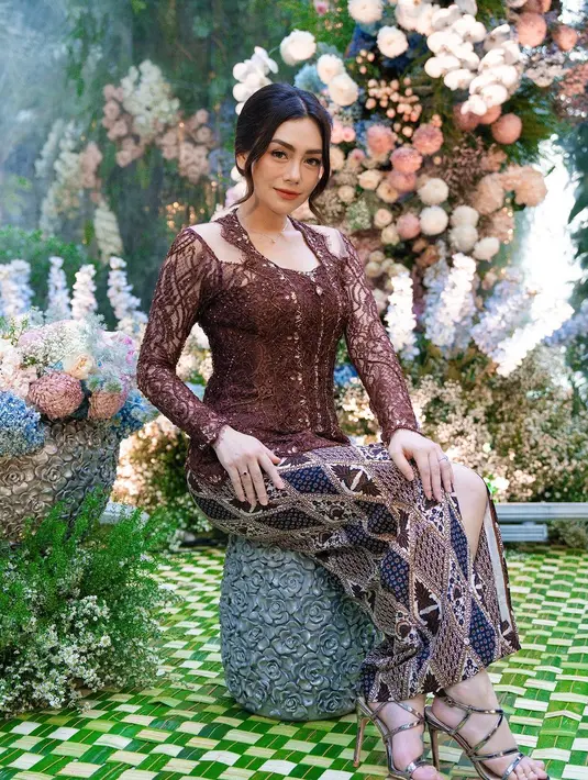 Penampilan anggun Celine kemudian dilengkapi dengan rok batik berwarna coklat, heels, pulasan makeup flawless, serta tatanan rambut sanggul rendah.