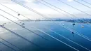 Pekerja menghilangkan es dari kabel Jembatan Russky yang melintasi Selat Bosphorus Timur di Vladivostok, Rusia, Senin (30/11/2020). Primorye dilanda hujan yang membekukan pada 18 November. (AP Photo/Aleksander Khitrov)