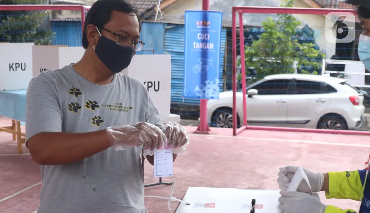 Pemiilih mengenakan sarung tangan plastik saat menggunakan hak suaranya dalam Pilkada Tangerang Selatan di TPS 23 Pondok Jagung Timur, Rabu (9/12/2020). Menggunakan masker hingga memakai sarung tangan plastik menjadi hal wajib saat melakukan pencoblosan di Pilkada 2020. (Liputan6.com/Angga Yuniar)