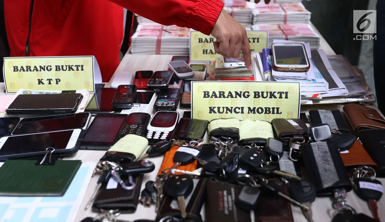 Petugas menunjukkan barang bukti saat rilis kasus pemalsuan dokumen dan uang palsu di Jakarta, Rabu (20/12). Bareskrim Polri menangkap sebanyak 13 tersangka yang mulai beroperasi sejak 2014 di wilayah Jakarta dan Jawa Barat. (Liputan6.com/Angga Yuniar)