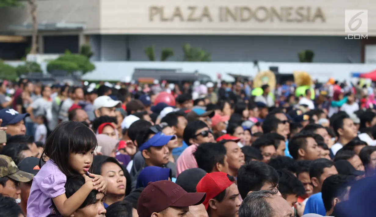 Seorang anak dibopong saat menyaksikan peresmian pengoperasian Moda Raya Terpadu Jakarta fase 1 di Kawasan Bundaran HI, Jakarta, Minggu (24/3). Peresmian dilakukan oleh Presiden Joko Widodo, Gubernur DKI Jakarta, Anies Baswedan serta pihak terkait. (Liputan6.com/Helmi Fithriansyah)
