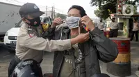 Anggota polisi dari Polsek Parung membantu memasangkan masker kepada pengendara sepeda motor di depan Polsek Parung, Kabupaten Bogor, Jawa Barat, Rabu (2/9/2020). Pembagian masker gratis setiap usai apel ini inisiatif anggota sejak masa pandemi COVID-19. (merdeka.com/Dwi Narwoko)