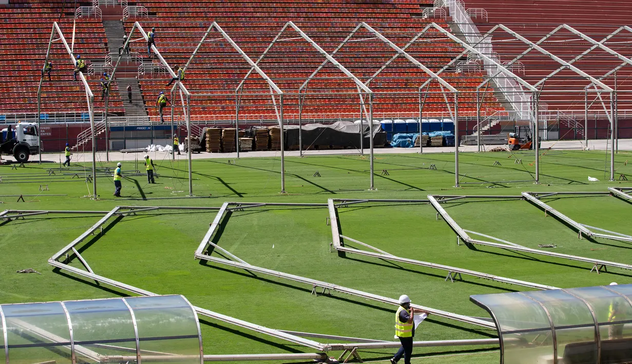 Pekerja membangun rumah sakit darurat bagi pasien terinfeksi Covid-19 di lapangan stadion Pacaembu, di Sao Paulo, Senin (23/3/2020). Sejumlah klub sepakbola papan atas Brasil meminjamkan stadion ke otoritas setempat untuk diubah menjadi rumah sakit atau klinik darurat virus corona. (AP/Andre Penner)
