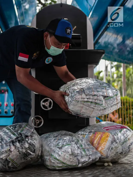 Petugas bersiap memasukkan barang bukti psikotropika ke dalam alat pembakar di Kejaksaan Negeri Jakarta Barat, Selasa (11/12). Barang bukti yang dimusnahkan berupa senjata Api, psikotropika, makanan, obat-obatan dan kosmetika. (Liputan6.com/Faizal Fanani)