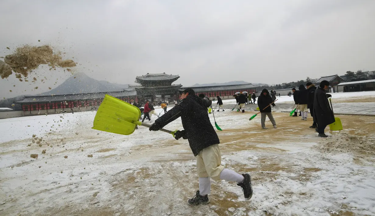Pekerja membersihkan salju di istana Gyeongbokgung setelah salju turun Seoul, Korea Selatan (15/2). Istana ini hancur pada saat invasi Jepang ke Korea tahun 1592-1598dan dibangun lagi selama tahun 1860-an. (AFP Photo/Jung Yeon-je)