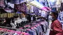 Pedagang mengamati pengunjung memilih pakaian bekas impor di Pasar Senen, Jakarta, Kamis (4/3/2021). Sepinya penjualan diperparah dengan rumor pakaian bekas impor berpotensi menyebarkan virus COVID-19. (merdeka.com/Iqbal S. Nugroho)