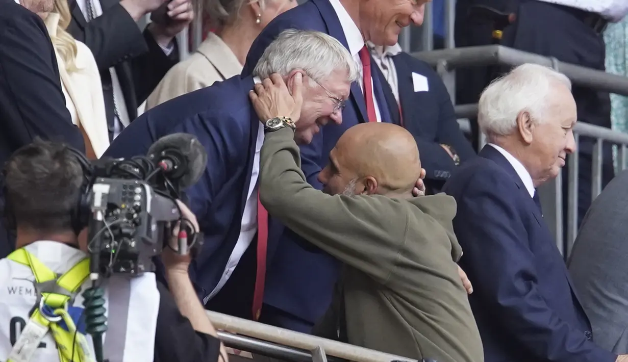 Pelatih Manchester City, Pep Guardiola bersalaman dengan Mantan manajer Manchester United Sir Alex Ferguson saat bersiap mengangkat trofi Piala FA. (AP Photo/Dave Thompson)