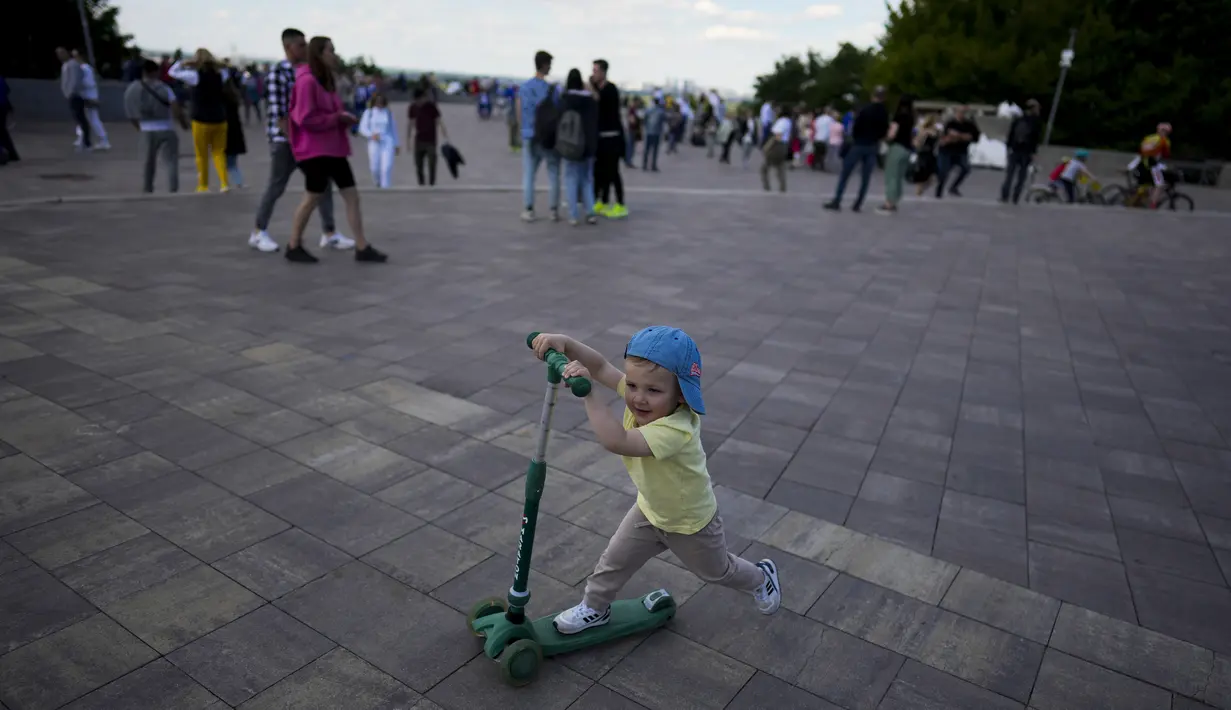 Seorang anak mengendarai skuter selama perayaan Hari Kiev di Kiev, Ukraina, Minggu (29/5/2022). Ibu kota Ukraina merayakan ulang tahun pendiriannya setiap Minggu terakhir bulan Mei. Kiev merayakan peringatan 1540 tahun pendiriannya, di mana tahun ini dirayakan di bawah darurat militer. (AP Photo/Natacha Pisarenko)