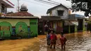 Anak-anak melintasi banjir yang melanda kawasan bantaran kali Cisadane, Tangerang, Jumat (26/4). Banjir kiriman setinggi 2 meter sempat melanda kawasan akibat curah hujan yang tinggi di bogor membuat derasnya air mengalir jauh sampai ke tempat ini. (Liputan6.com/Johan Tallo)