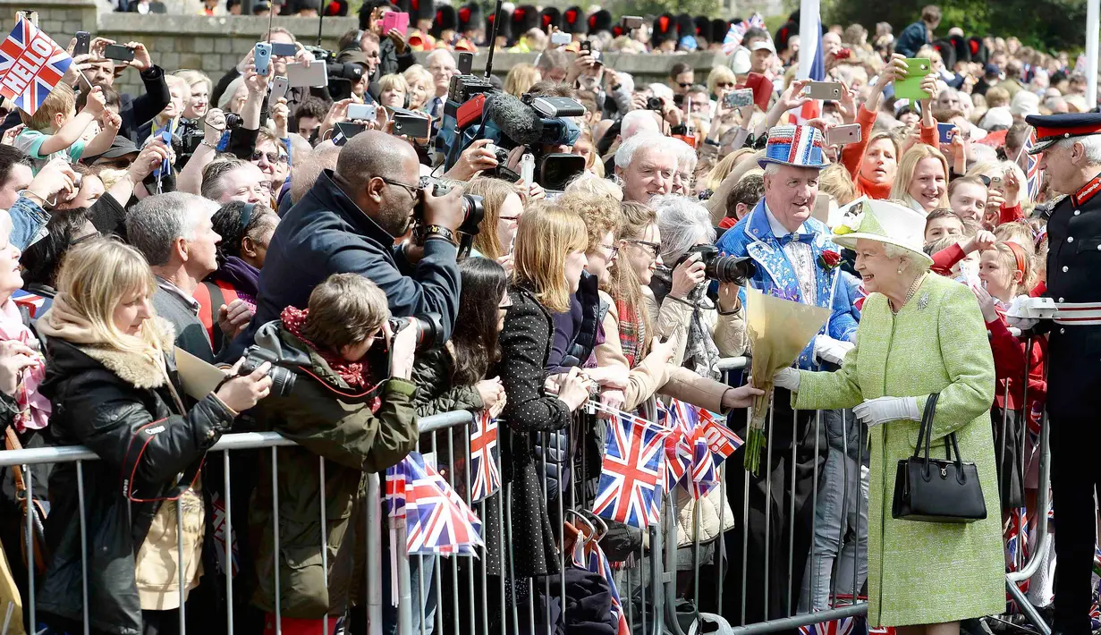 Ratu Inggris Elizabeth II menerima bunga dari warga saat merayakan ulang tahunnya yang ke-90  di kawasan Istana Windsor, Berkshire, Inggris (21/4/2016). (AFP PHOTO/John Stillwell)
