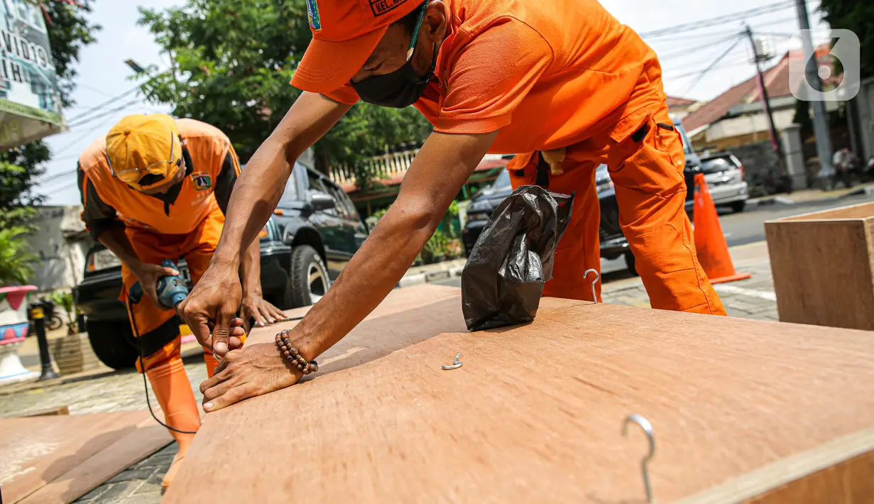 Petugas PPSU memproduksi peti jenazah di halaman Kantor Kelurahan Kayu Putih, Jakarta, Selasa, (6/7/2021). Kelurahan Kayu Putih berinisiatif membuat peti jenazah dilatar belakangi warganya yang terkendala ketersediaan peti saat angka kematian COVID-19 meningkat di DKI. (Liputan6.com/Faizal Fanani)