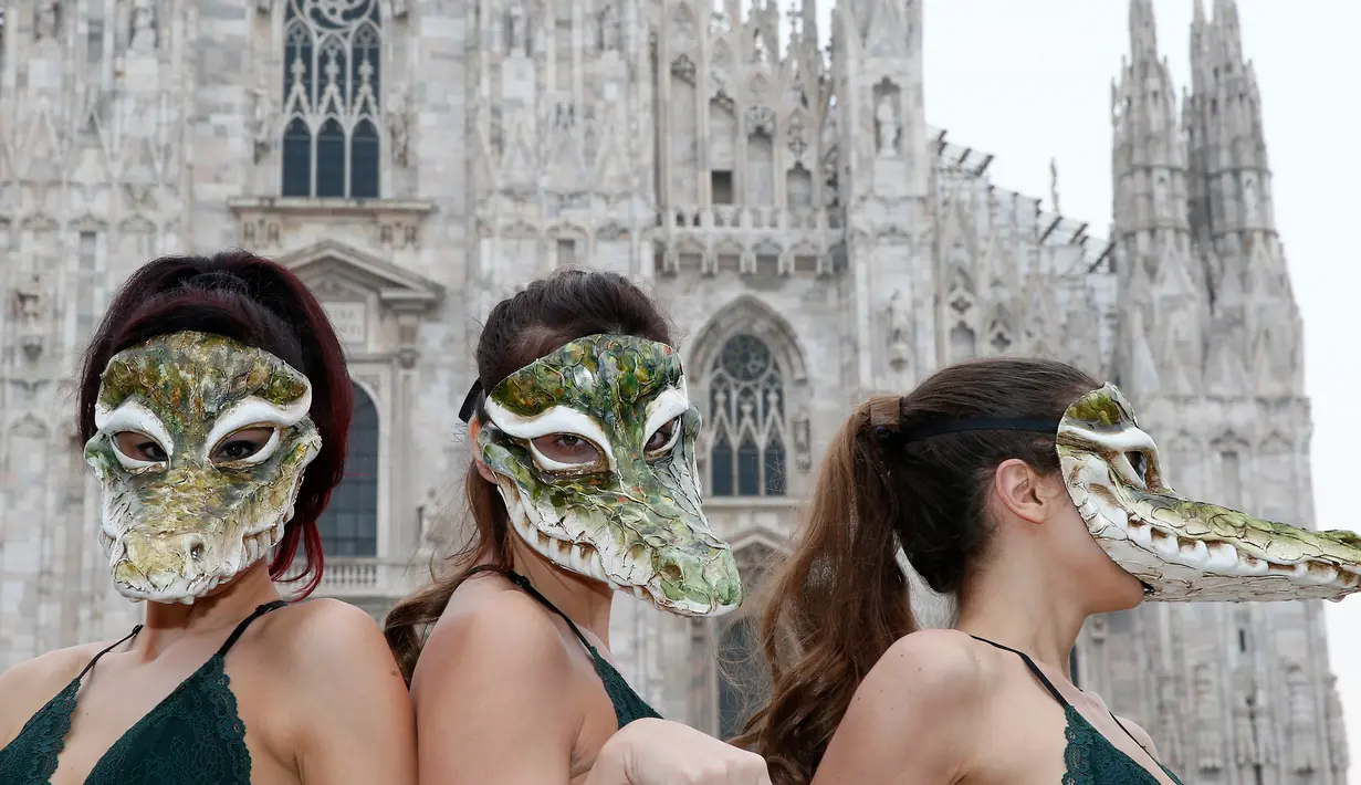 Sejumlah wanita dari Aktivis PETA mengenakan topeng buaya saat menggelar unjuk rasa jelang Milan Fashion Week di Milan Duomo Square, Italia, Selasa (21/2). Mereka mengecam produk fashion yang terbuat dari kulit hewan. (AP Photo/Antonio Calanni)