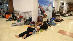 Wisatawan asing tidur di lantai saat menunggu jadwal keberangkatan pesawat di Bandara Internasional Praya Lombok, NTB, Senin (6/8). Imbas gempa 7 SR, para wisatawan terlantar di bandara karena jam pemberangkatan pesawat yang tertunda (AFP/SONNY TUMBELAKA)