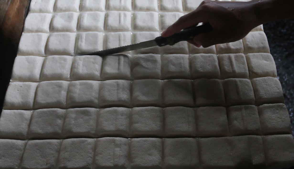 Di sisi lain Badan Pangan Nasional memastikan pengawasan terhadap importir dan distributor kedelai terus dilakukan agar harga jual tetap mengacu pada Harga Acuan Penjualan serta menjaga stabilitas pasokan bagi konsumen. Tampak dalam foto, perajin menyelesaikan pembuatan tahu di Duren Tiga Jakarta Selatan, Selasa 14 April 2026, di tengah kenaikan harga kedelai yang berdampak pada biaya produksi. (merdeka.com/Arie Basuki)