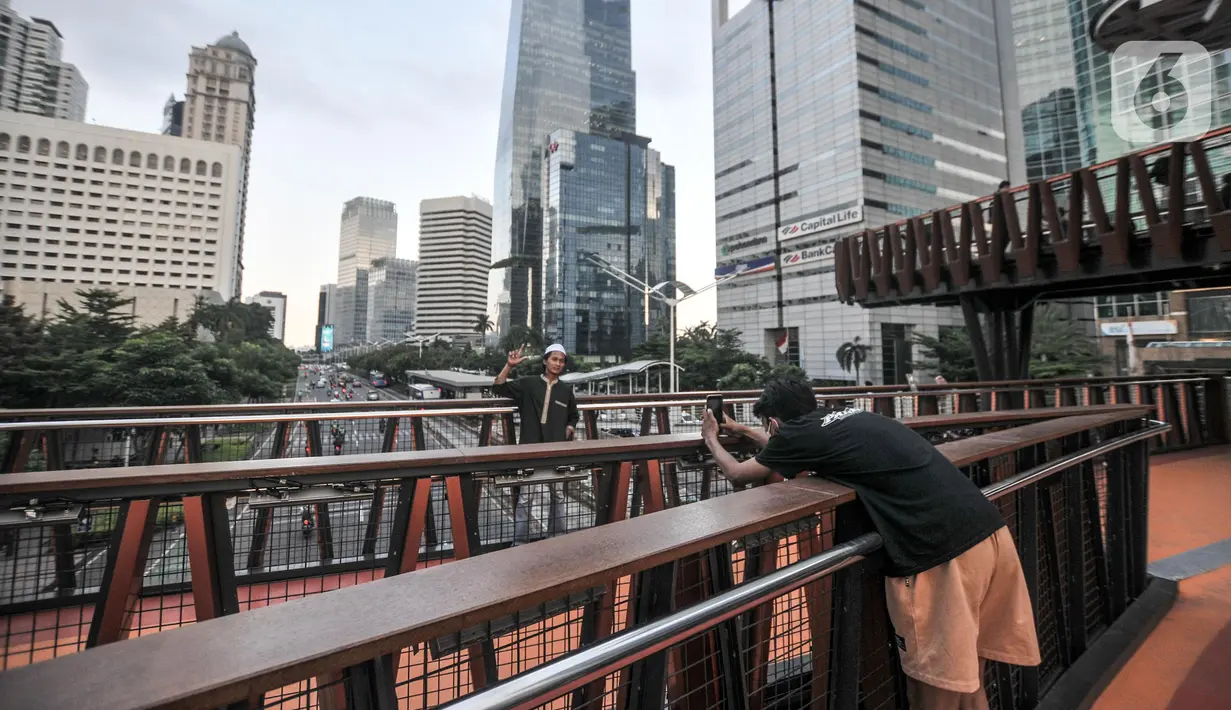 Warga berfoto saat ngabuburit di JPO Pinisi Pinisi Karet-Sudirman, Jakarta Pusat, Senin (4/4/2022). JPO Pinisi kini menjadi destinasi baru warga Jakarta untuk menunggu waktu berbuka puasa atau ngabuburit sambil menikmati suasana perkotaan. (merdeka.com/Iqbal S. Nugroho)