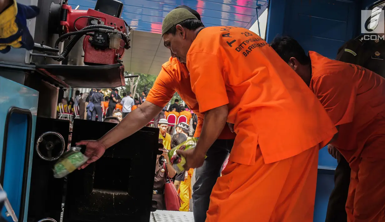 Tersangka memasukkan barang bukti narkoba ke dalam mesin insimilator saat pemusnahan di Bareskrim Mabes Polri, Jakarta, Selasa (9/7/2019). Bareskrim Polri memusnahkan 177,5 Kg sabu dan 30 ribu butir ekstasi yang disita dari jaringan Malaysia-Indonesia. (Liputan6.com/Fazail Fanani)