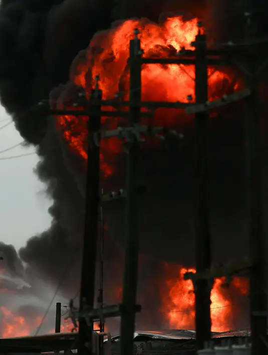 Petugas memadamkan kebakaran tempat penyimpanan bahan petrokimia di Intercontinental Terminals Co (ITC) di Deer Park, Texas, Senin (18/3). Kebakaran terjadi di terminal yang menyimpan cairan dan gas petrokimia. (Godofredo Vasquez/Houston Chronicle via AP)