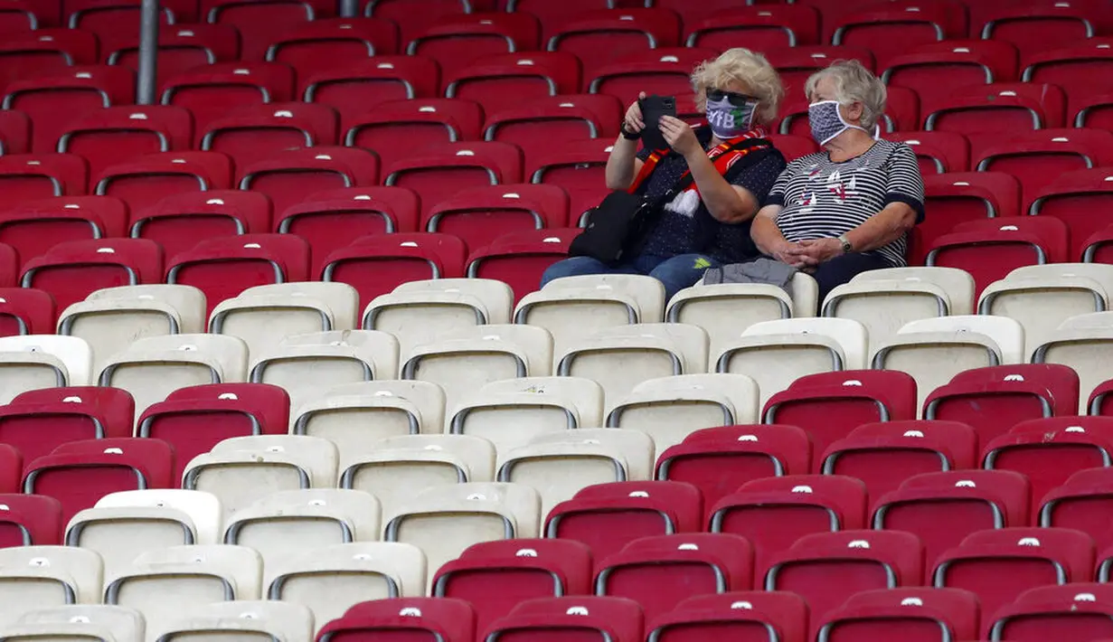 Dua orang penonton saat menyaksikan pertandingan antara  VfB Stuttgart melawan SC Freiburg pada laga Bundesliga, Sabtu (19/9/2020). Sejumlah liga di Eropa telah mengijinkan fans menonton langsung pertandingan di stadion. (AP Photo/Matthias Schrader)