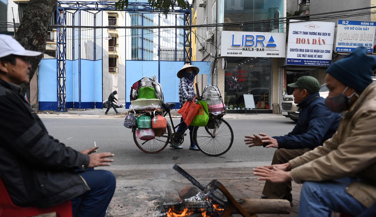 Sejumlah orang membakar kayu untuk menghangatkan diri pada hari musim dingin di Hanoi, Vietnam, Jumat (8/1/2021). Vietnam tahun ini diperkirakan mengalami musim dingin yang lebih dingin dari biasanya ketika suhu permukaan laut Samudra Pasifik turun, membentuk fenomena La Nina. (Nhac NGUYEN/AFP)
