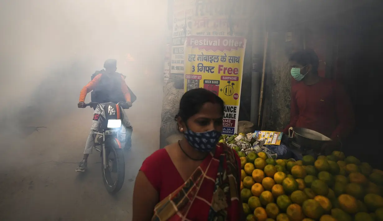Komuter berjalan melewati asap dari fogging di daerah padat penduduk di New Delhi, India, Rabu (27/10/2021). New Delhi telah melaporkan ratusan kasus demam berdarah, dengan lebih dari 200 kasus baru dalam seminggu terakhir, menurut laporan yang dirilis pada hari Senin. (AP Photo/Manish Swarup)