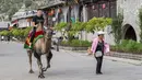 Seorang wisatawan menaiki seekor unta di kota kuno Qikou di Wilayah Linxian, Lyuliang, Provinsi Shanxi, China utara, pada 9 Juni 2020. (Xinhua/Yang Chenguang)