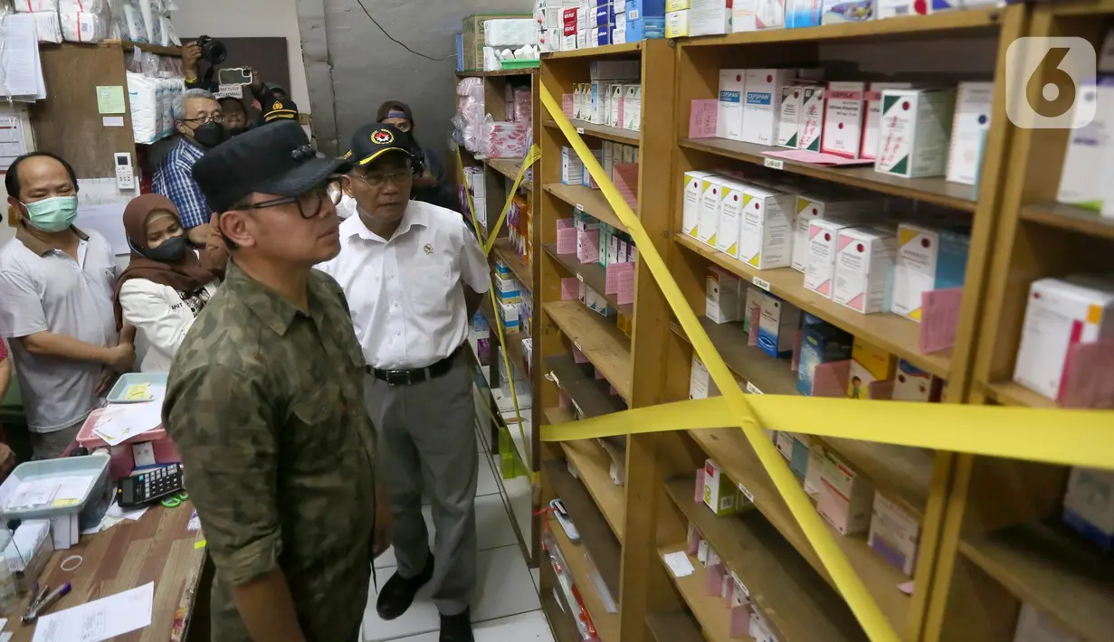Menteri Koordinator Bidang Pembangunan Manusia dan Kebudayaan (Menko PMK) Muhadjir Effendy (kanan) bersama Wali Kota Bogor Bima Arya (kedua kanan) memasang tanda larangan peredaran obat sirup anak saat sidak di Depo Farmasi Poliklinik Afiat RS PMI, Bogor, Jawa Barat, Sabtu (22/10/2022). Sidak dilakukan pada depo farmasi dan dua apotek di Kota Bogor menyusul terbitnya surat edaran nomor SR.01.05/III/3461/2022 dari Kementerian Kesehatan tentang penghentian sementara penggunaan obat dan vitamin dalam bentuk cair atau sirup kepada anak-anak. (merdeka.com/Arie Basuki)