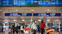Penerbangan dari Wuhan Ditutup: Pelancong berjalan melintasi papan informasi tentang penerbangan dari Wuhan telah dibatalkan di Bandara Internasional Ibu Kota Beijing pada Kamis (23/1/2020). China menangguhkan semua transportasi dari dan ke kota pusat penyebaran virus corona. (AP/Mark Schiefelbein)