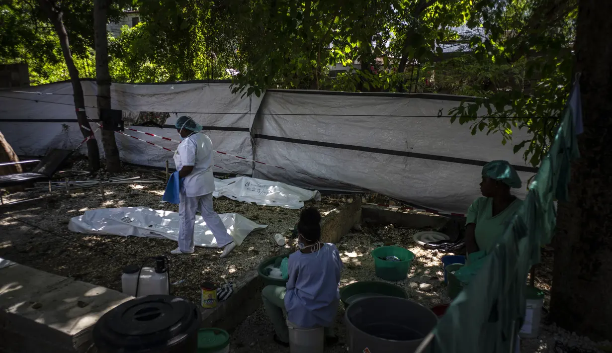 Seorang dokter berjalan di samping tubuh Stanley Joliva dan orang tak dikenal lainnya, yang meninggal saat menunjukkan gejala kolera di sebuah klinik yang dijalankan oleh Doctors Without Borders di Port-au-Prince, Haiti, Kamis, 27 Oktober 2022. Untuk pertama kalinya dalam tiga tahun, orang-orang di Haiti telah sekarat karena kolera, meningkatkan kekhawatiran tentang skenario yang berpotensi menyebar cepat dan menghidupkan kembali ingatan tentang epidemi yang menewaskan hampir 10.000 orang satu dekade lalu. (AP/Ramon Espinosa)
