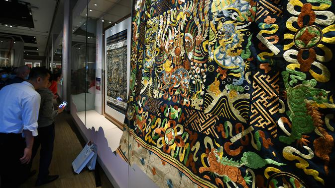 Orang-orang mengamati selimut quilt dengan pola naga dalam pameran selimut quilt di Museum Hainan di Haikou, Provinsi Hainan, China pada 13 November 2020. Pameran yang berlangsung sebulan penuh tersebut menampilkan 41 selimut quilt dengan bordir naga Li yang indah. (Xinhua/Guo Cheng)