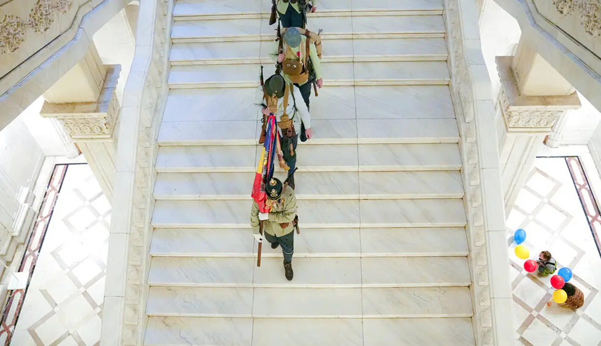 Sejumlah pria yang mengenakan seragam militer kuno berjalan menuruni tangga Istana Parlemen pada Hari Anak Internasional, Bucharest, Rumania, Selasa (1/6/2021). Lebih dari 10 ribu anak-anak dan orang dewasa mengunjungi gedung era komunis yang juga dikenal House of the People. (AP Photo/Vadim Ghirda)