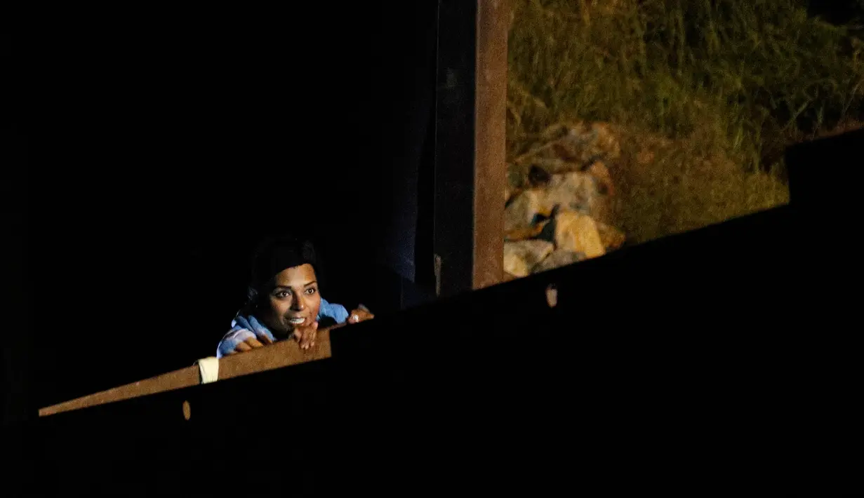 Seorang wanita memanjat pagar perbatasan AS, berencana untuk menyerah kepada penjaga perbatasan saat ia menyeberang dari Playas de Tijuana, Meksiko (3/12). (AP Photo/Rebecca Blackwell)