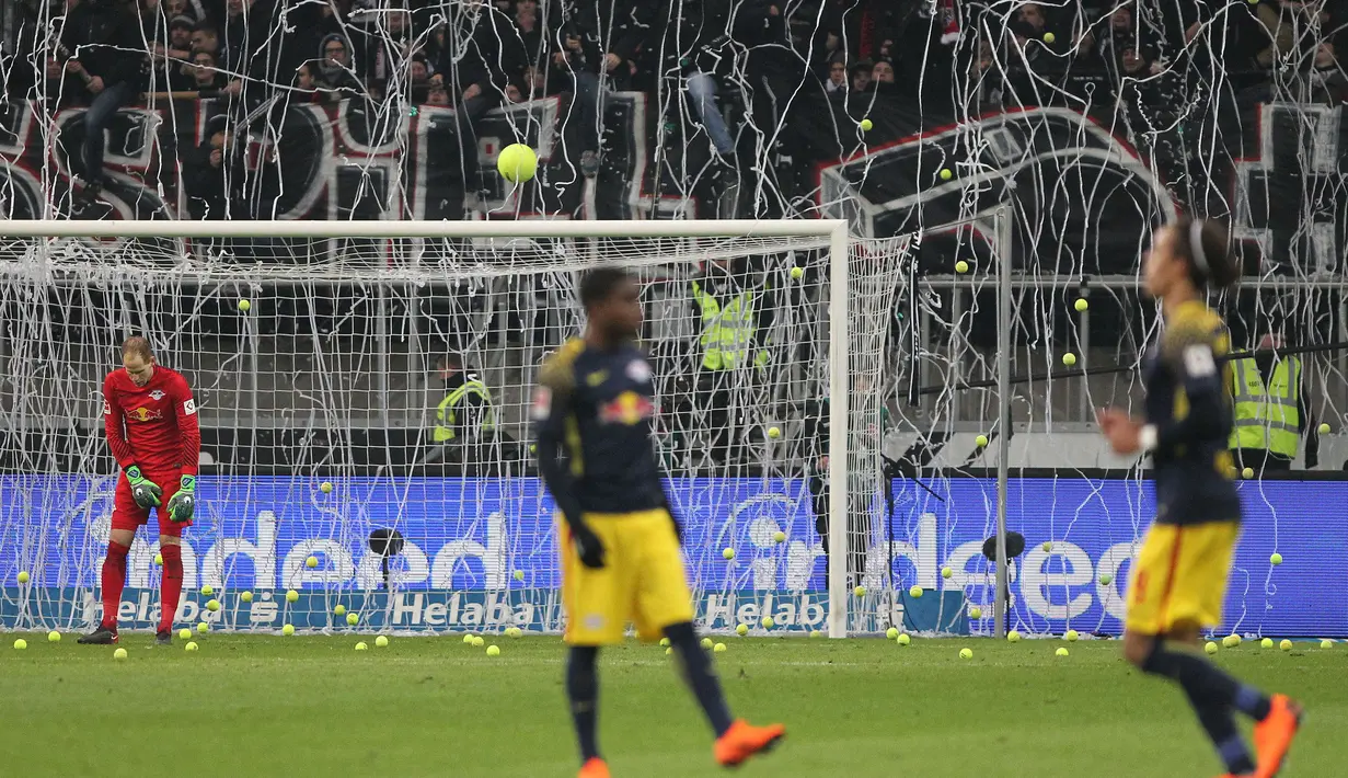 Bola tenis dan tisu toilet dilemparkan ke lapangan dan gawang pada Kick-off  laga Eintracht Frankfurt vs RB Leipzig di Stadion Commerzbank Arena, Senin (19/2). Penggemar mencemooh dan bersiul pada sebagian besar jalannya pertandingan. (DANIEL ROLAND/AFP)
