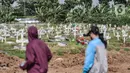 Warga melintas di kompleks pemakaman khusus Covid-19 di TPU Rorotan, Jakarta, Rabu (2/3/2022). Lurah Rorotan Idham Mugabe mengungkapkan sejak digunakan pada Maret 2021, saat ini luas lahan TPU Rorotan mencapai 25 hektare dan telah terisi sebanyak 6.388 petak makam. (merdeka.com/Iqbal S Nugroho)