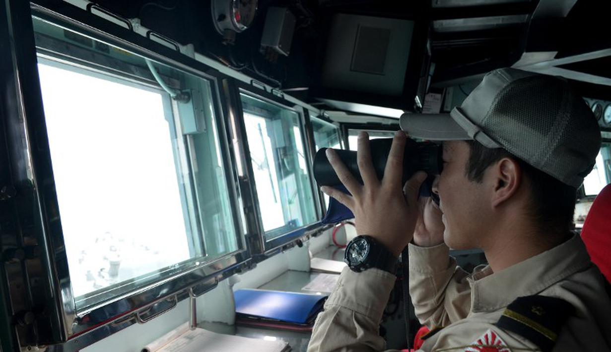 Seorang anggota Angkatan Laut Jepang memantau laut untuk mencari puing-puing AirAsia QZ8501 di Laut Jawa, Rabu (7/1/2015). (AFP Photo/Dewanto Samodro)