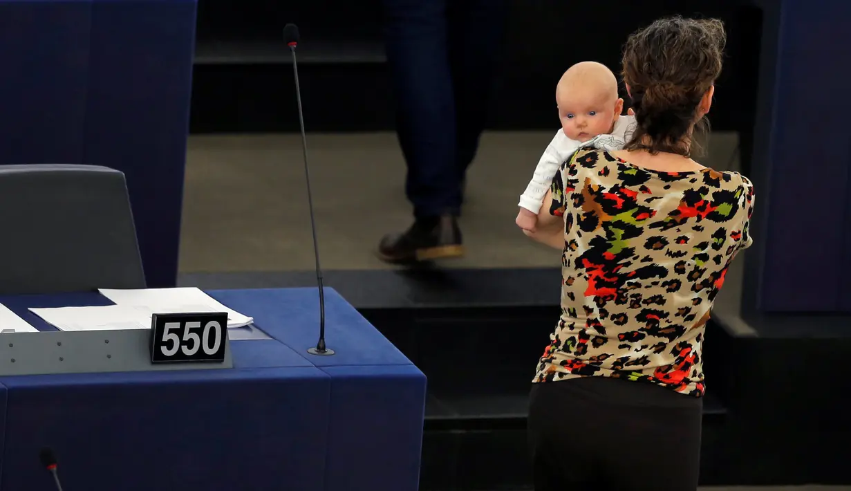 Anggota Parlemen Eropa Anneliese Dodds saat mencoba mendiamkan anaknya yang diajak rapat di kantor Parlemen Eropa, Strasbourg , Perancis , 14 April 2016. Wanita ini tampak santai menikmati rapat sambil mengasuh anaknya.  (REUTERS / Vincent Kessler)