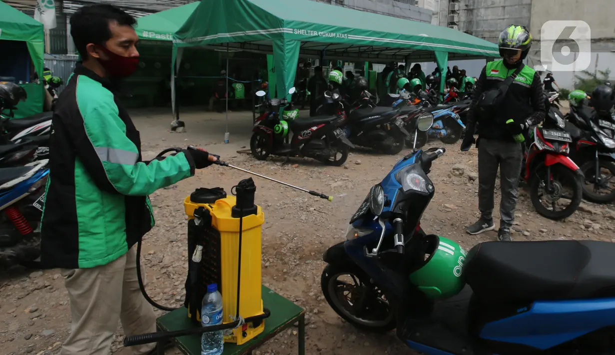 Pengemudi ojek online melakukan penyemprotan disinfektan sebelum mengangkut penumpang di Shelter Sudirman, Jakarta, Senin (8/6/2020). Pemprov DKI mulai mengizinkan ojek daring maupun konvensional mengangkut penumpang di PSBB transisi dengan menerapkan protokol kesehatan. (Liputan6.com/Angga Yuniar)