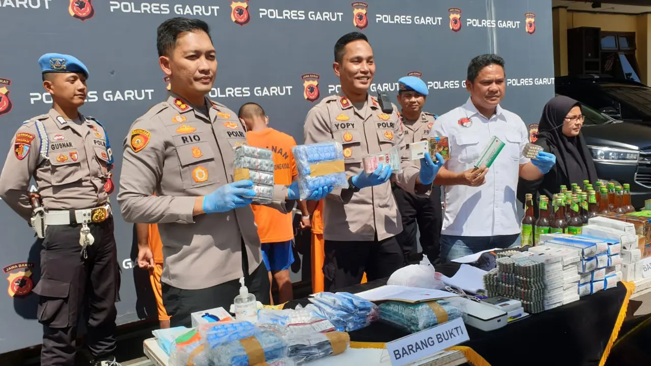 Kapolres Garut AKBP Rio Wahyu Anggoro bersama Wakapolres dan Kasatnarkoba Polres Garut menujukan barang bukti puluhan ribu butir obat keras terbatas dan ratusan botol jamu ilegal. (Liputan6.com/Jayadi Supriadin),