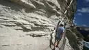 Turis menyusuri jalan setapak di kaki tebing sebelum menaiki tangga Raja Aragon di Bonifacio di pulau Corsica, Mediterania Prancis (19/9/2021). Tangga Raja Aragon digali dengan tangan di tebing batu kapur di suatu malam oleh pasukan Raja Aragon tahun 1420. (AFP/Pascal Pochard-Casabianca)